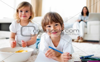 Smiling siblings eating chips and drawing 