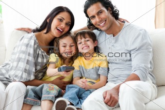 Cute family watching TV together sitting on a sofa