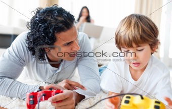 Father and his son playing video games lying on the floor