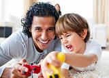 Excited little boy and his father playing video games lying on t
