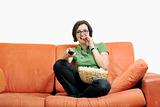 young woman eats popcorn on orange sofa