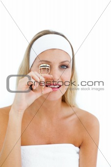Attractive woman using an eyelash curler