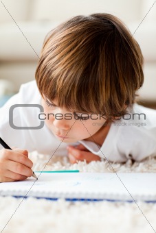 Little boy drawing lying on the floor in the living-room