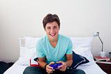 Happy teenager playing video games in his bedroom