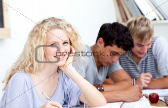 Smiling teen girl studying in the library with her friends