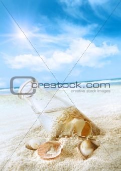 Bottle with seashells in the sand 