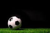 Soccer ball on grass against black