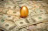 Gold nest egg on a layer of cash of various American banknote de