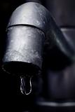 Old leaky faucet focus on water drop