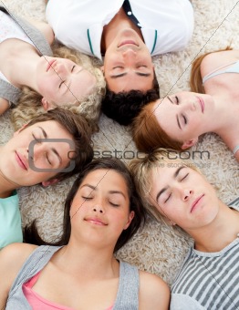 Teenagers with their heads together sleeping on the ground 