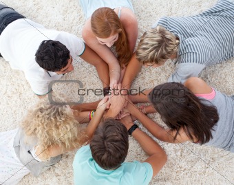 Teenagers lying on the floor in a circle playing hands games