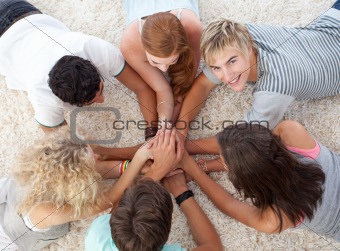 Teenagers lying on the floor with hands together
