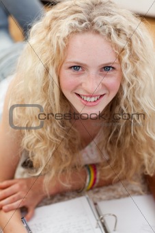 Portrait of a smiling teenager studying on the floor