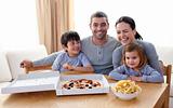 Happy young family eating a pizza in the living-room