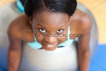 Smiling attractive woman doing push-ups with a gym ball