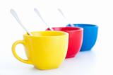 three colorful tea cups with spoons