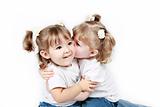 Adorable little twin girls kissing isolated on white background 