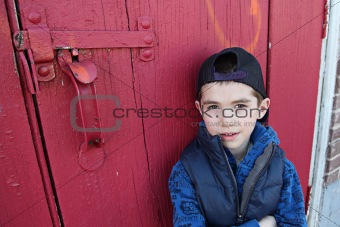 Young child hanging out near a grungy wall 