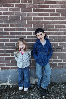 Young children hanging out near a grungy wall 