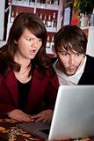 Woman and man staring with shock at laptop