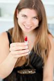 Smiling woman holding lipstick in the camera
