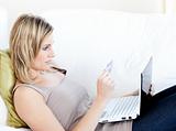 Attractive woman lying on a sofa with a laptop