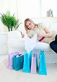 Cheerful woman lying on a couch with shopping bags