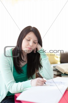 Tired young student sleeping while doing her homework 