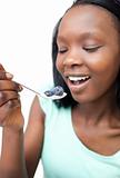 Afro-american woman eating a yogurt with blueberries 
