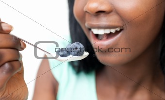 Close-up of a woman eating a yogurt with blueberries