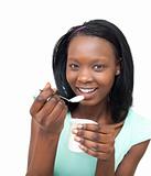 Cheerful young woman eating a yogurt