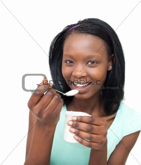 Cheerful young woman eating a yogurt