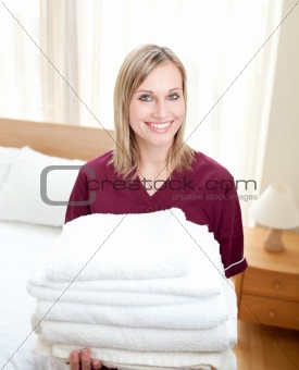 Smiing cleaning lady holding towels in a hotel room 