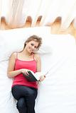 Smiling woman reading a book lying on her bed