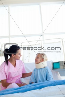 Little girl with a neck brace smiling at the nurse