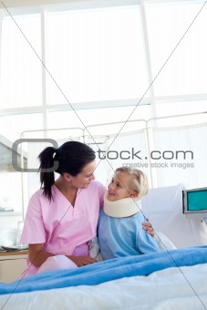 Smiling patient with a neck brace and her nurse in a hospital