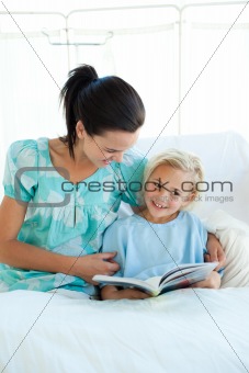 Girl on a hospital bed reading with her mother 