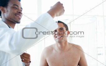 Smiling doctor checking male patient's temperature