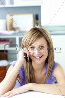 Cheerful woman answering the phone in the kitchen 