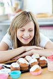 Cheerful woman looking at cakes in the kitchen 