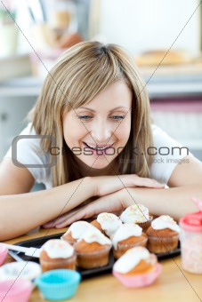 Cheerful woman looking at cakes in the kitchen 