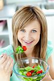 Delighted woman eating a salad in the kitchen 