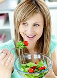 Cute woman eating a salad in the kitchen 