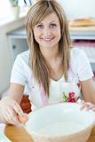 Portrait of a young woman preparing a cake in the kitchen