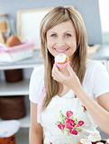 Delighted woman eating a little cake in the kitchen 