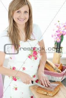 Radiant woman cutting bread in the kitchen 