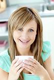 Delighted woman holding a cup of tea in the kitchen