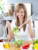 Smiling woman preparing a salad in the kitchen 