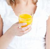 Close-up of a young woman holding an orange juice