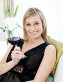 Beautiful woman drining red wine sitting on a sofa